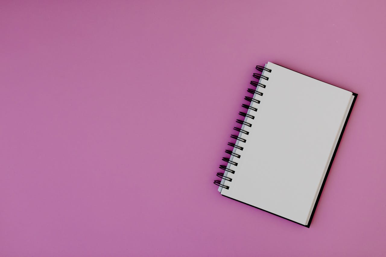 about-02 Top view of a spiral notebook on a pink background, suitable for mockups.
